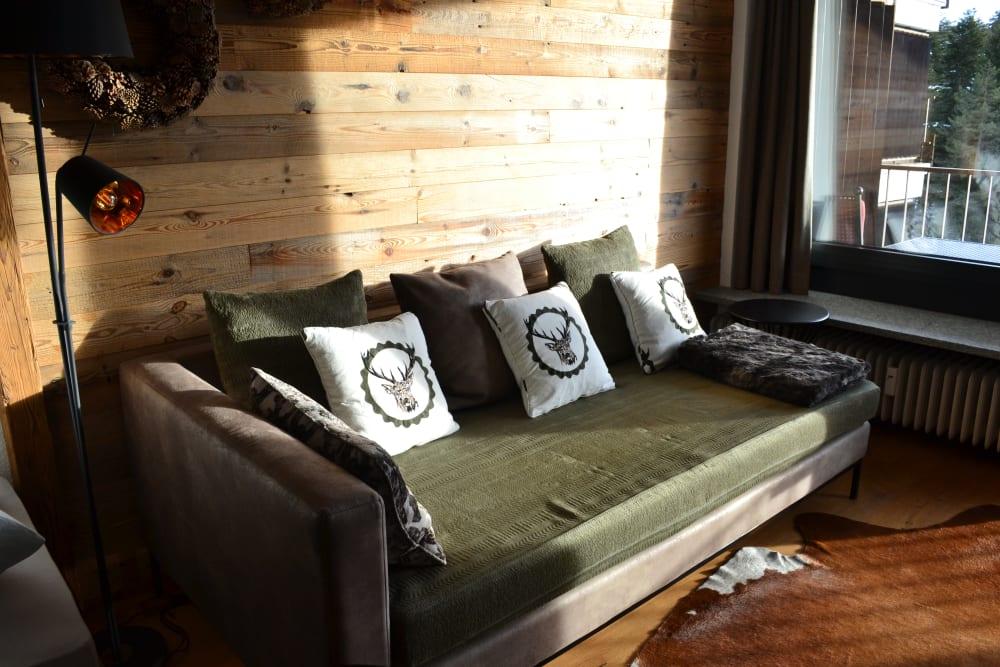 Sofa an der Altholzwand mit Tageslicht vom Balkon im Wilderer Nest
